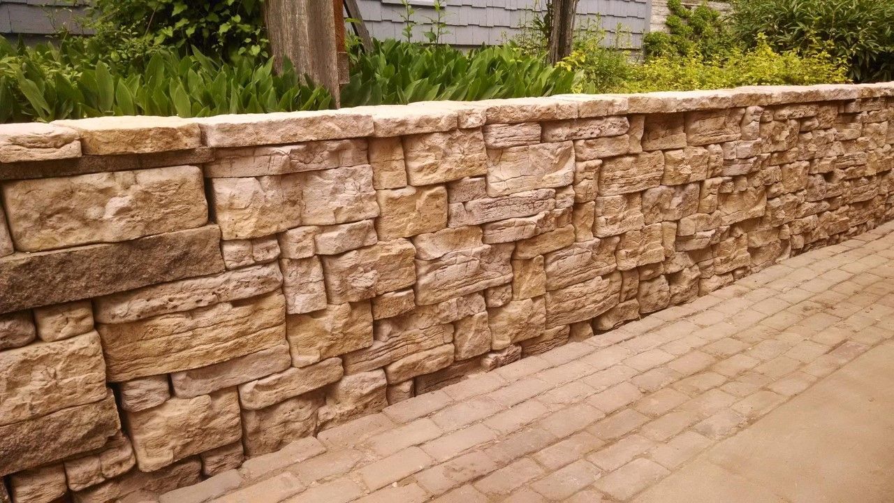 Stone retaining wall with light-colored bricks, built alongside a brick pathway