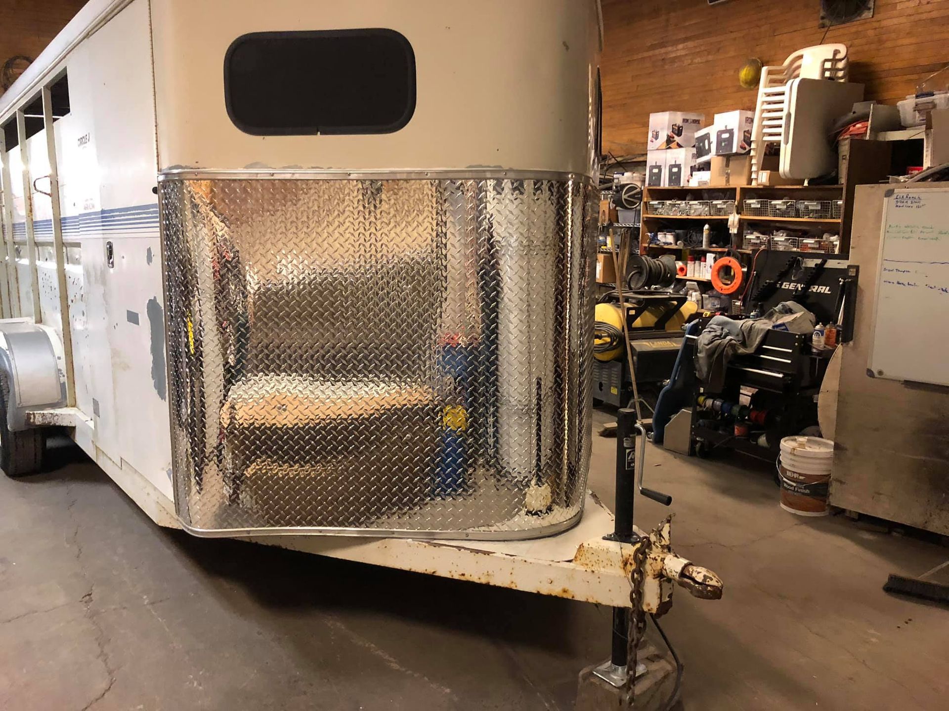A rv is sitting in a garage next to a pile of tires.