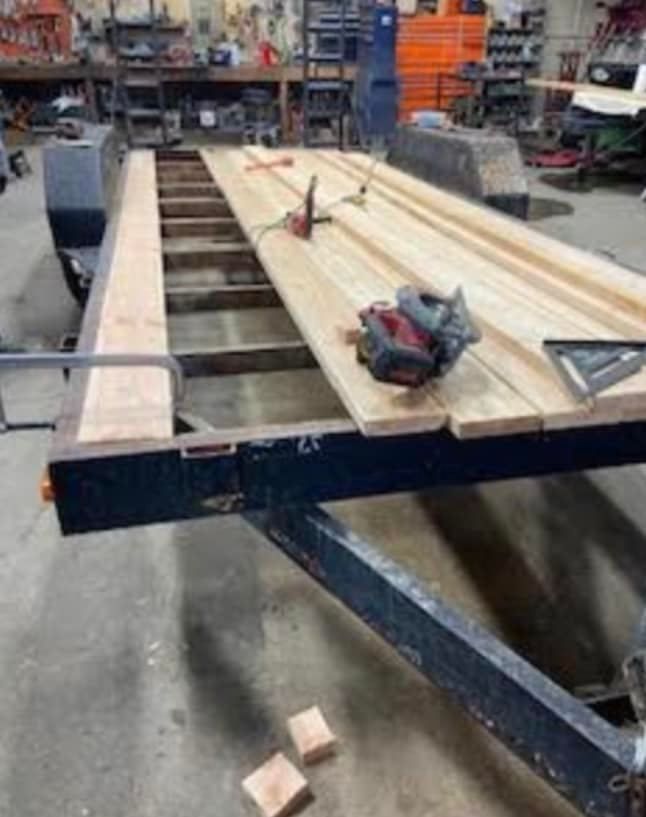 A wooden table is sitting on top of a trailer in a garage.