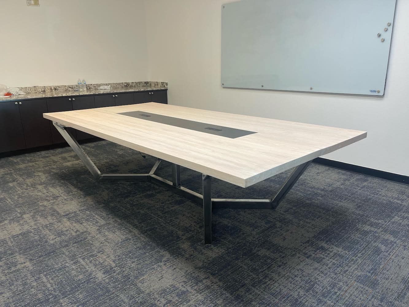 A conference room with a long table and a whiteboard on the wall.