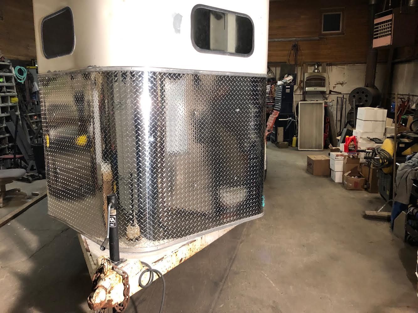 A horse trailer is sitting in a garage.