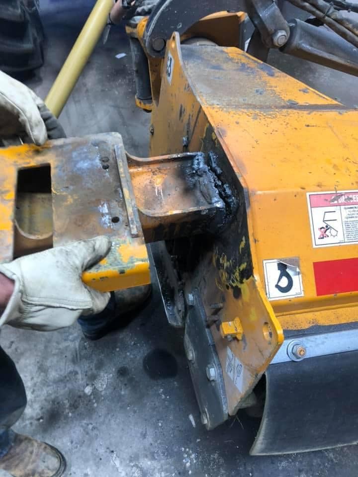 A person wearing gloves is working on a yellow machine.