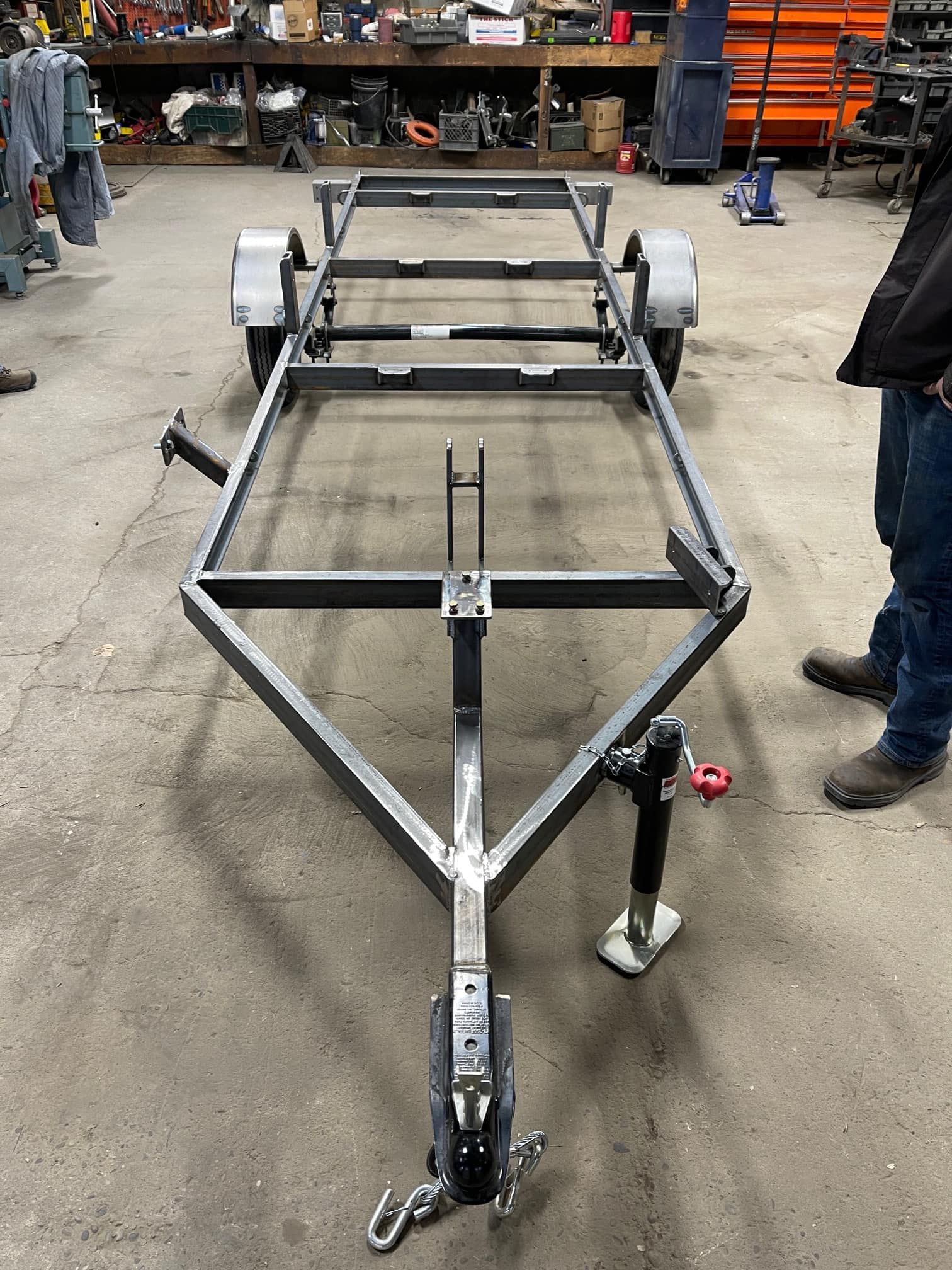 A man is standing next to a trailer that is being built in a garage.