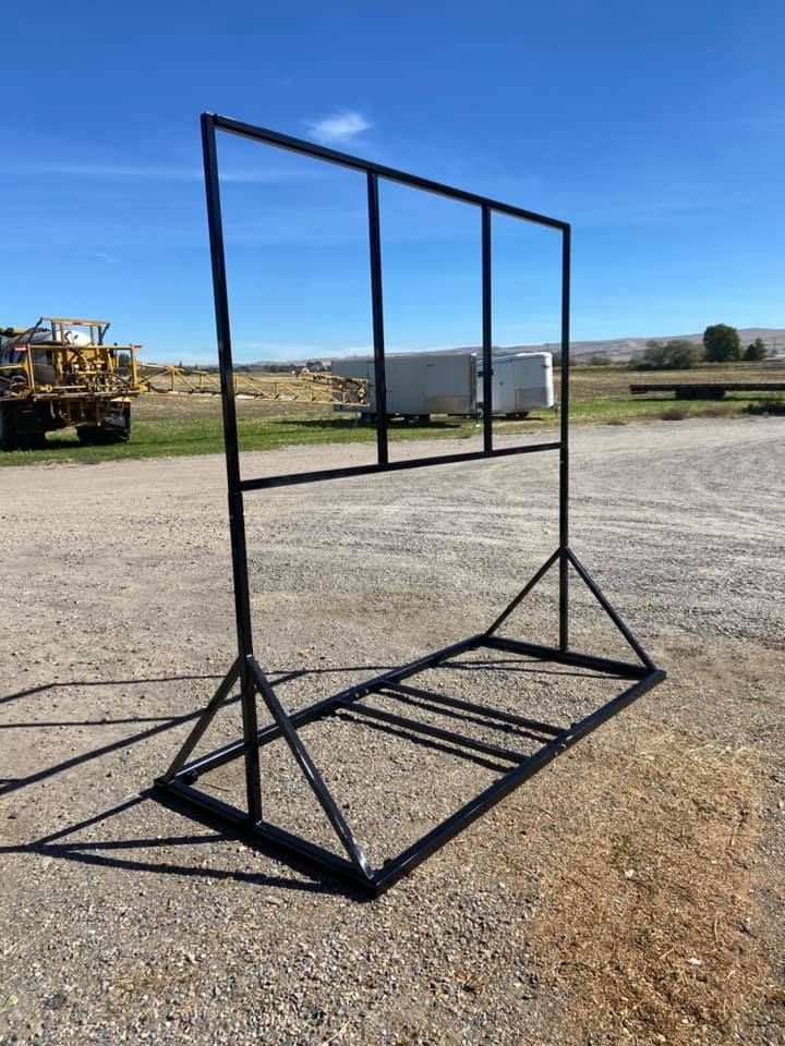 A large metal frame is sitting on top of a gravel road.