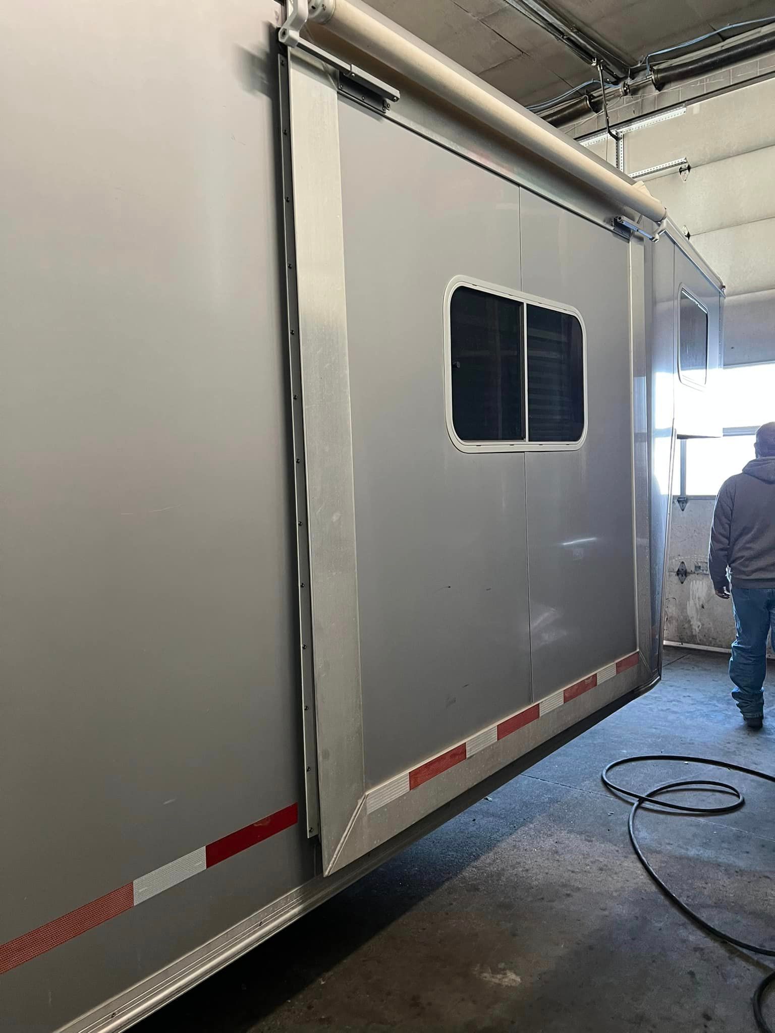 A man is standing next to a trailer in a garage.