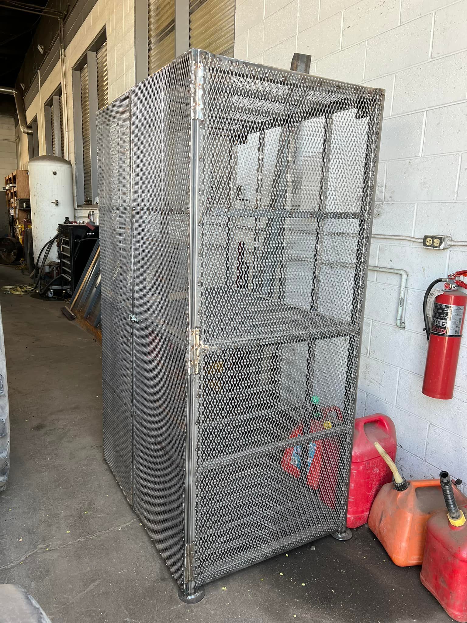 A metal cage is sitting in a garage next to a fire extinguisher.
