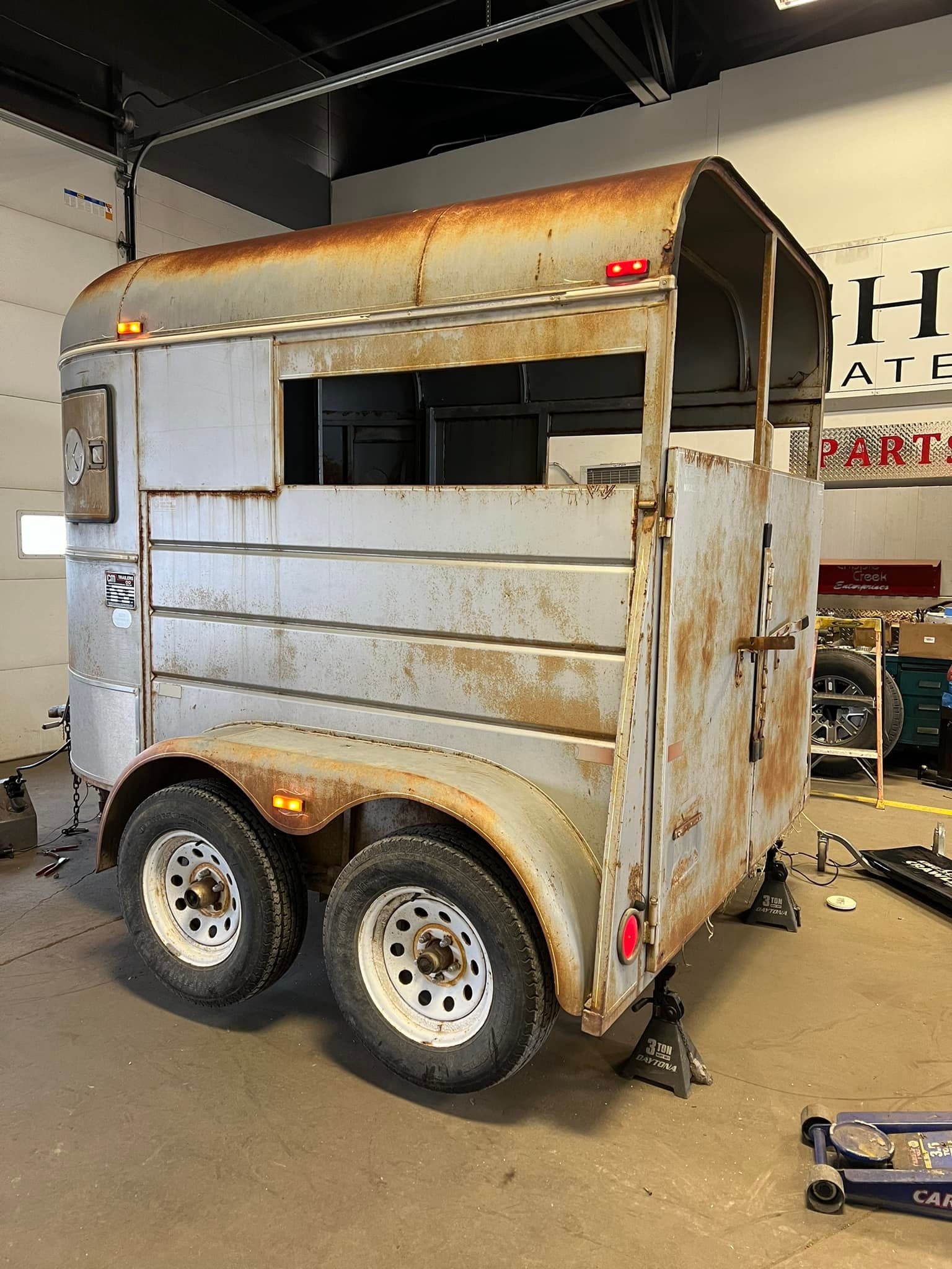 A horse trailer is sitting on the ground in a garage.
