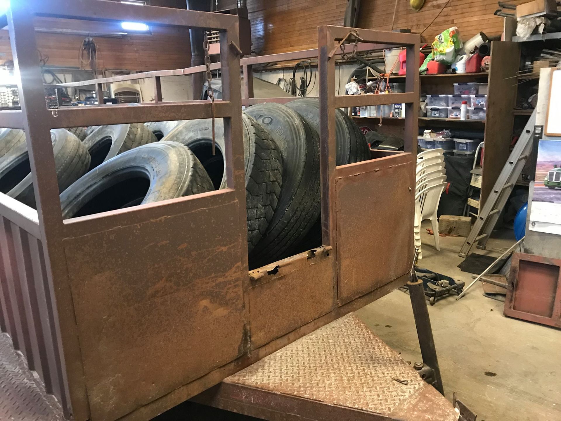 A bunch of tires are in a cage in a garage.