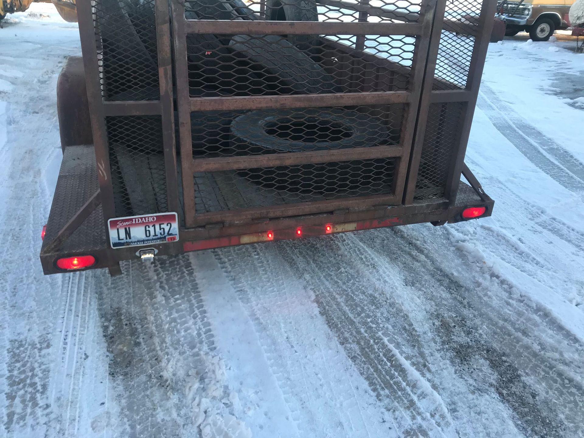A trailer with a tire on the back is driving down a snowy road.