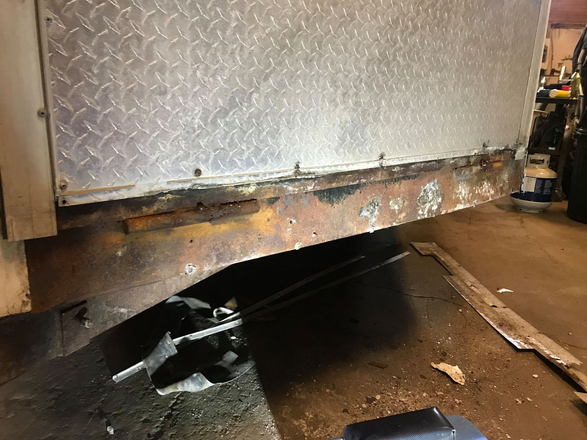 The side of a trailer is being repaired in a garage.