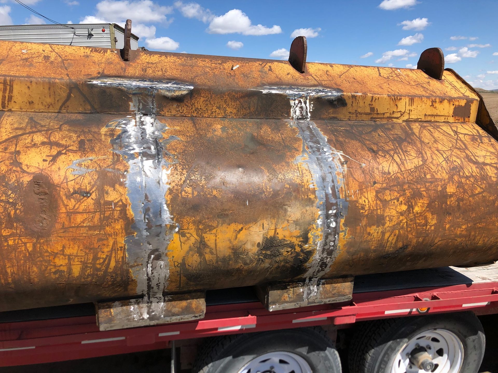 A large yellow tank is sitting on top of a red trailer.