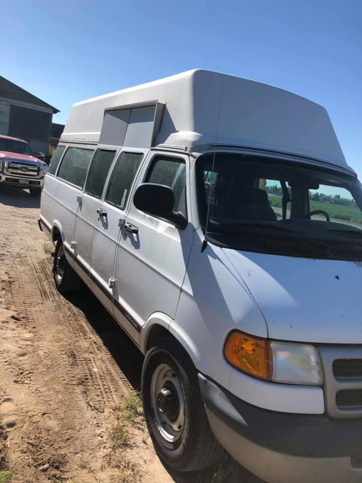 A white van is parked on a dirt road.