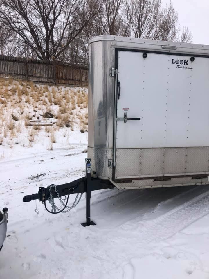 A trailer is parked in the snow on a snowy road.