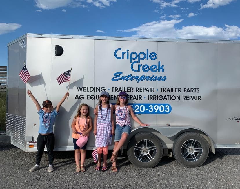 A group of children standing in front of a trailer that says cripple creek enterprises