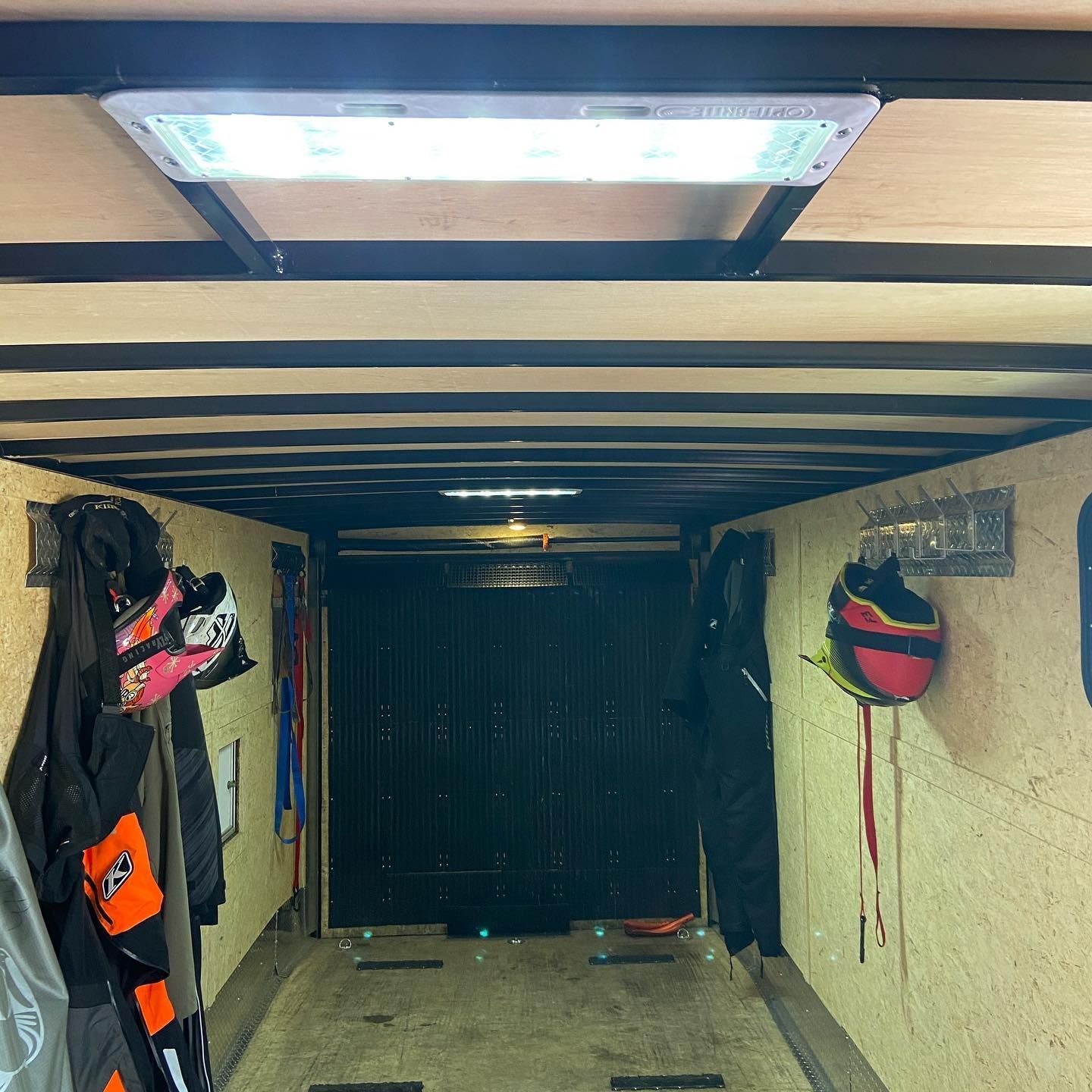 A long hallway with clothes and helmets hanging on the wall