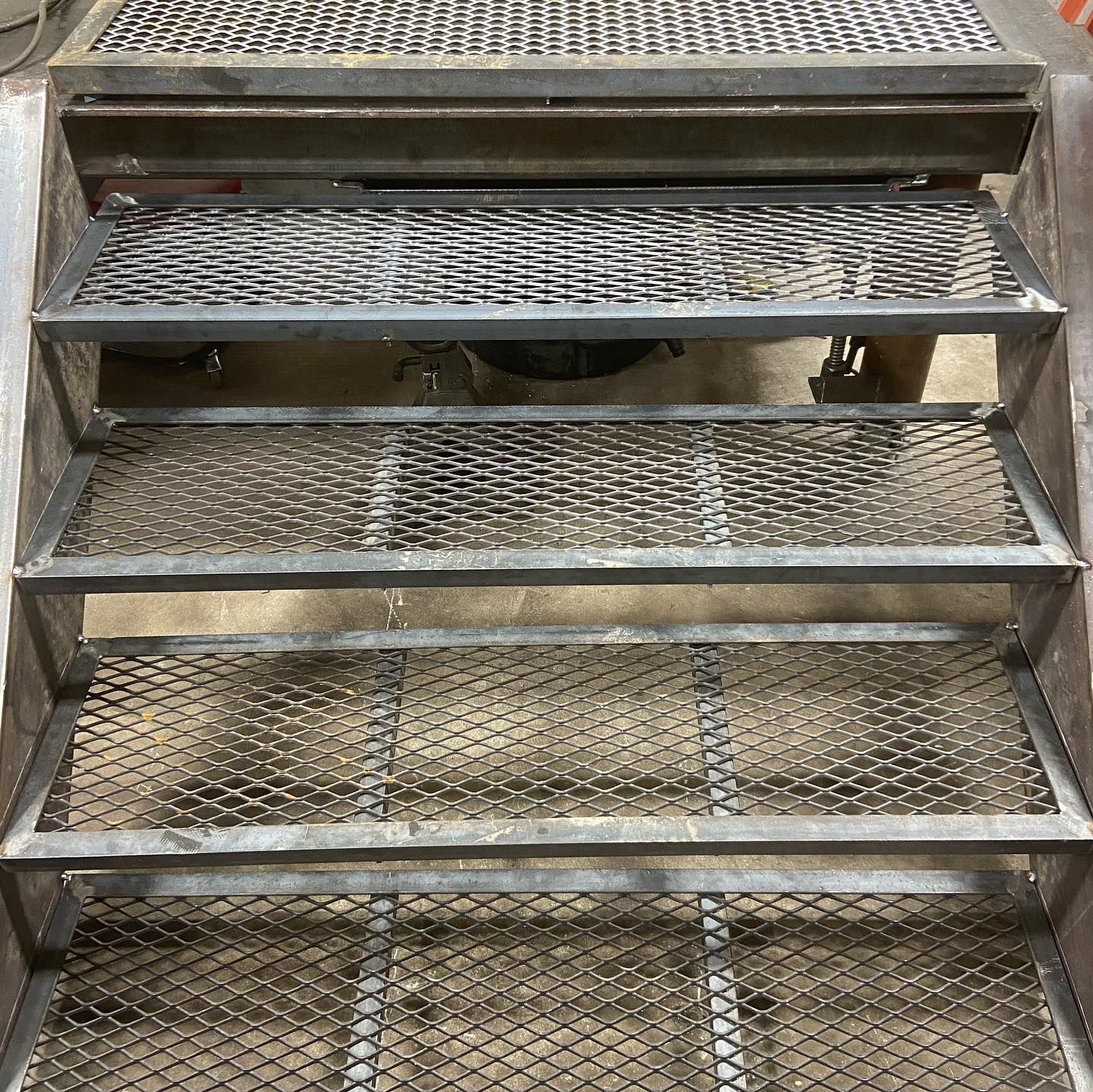 A close up of a metal staircase with a motorcycle parked behind it.