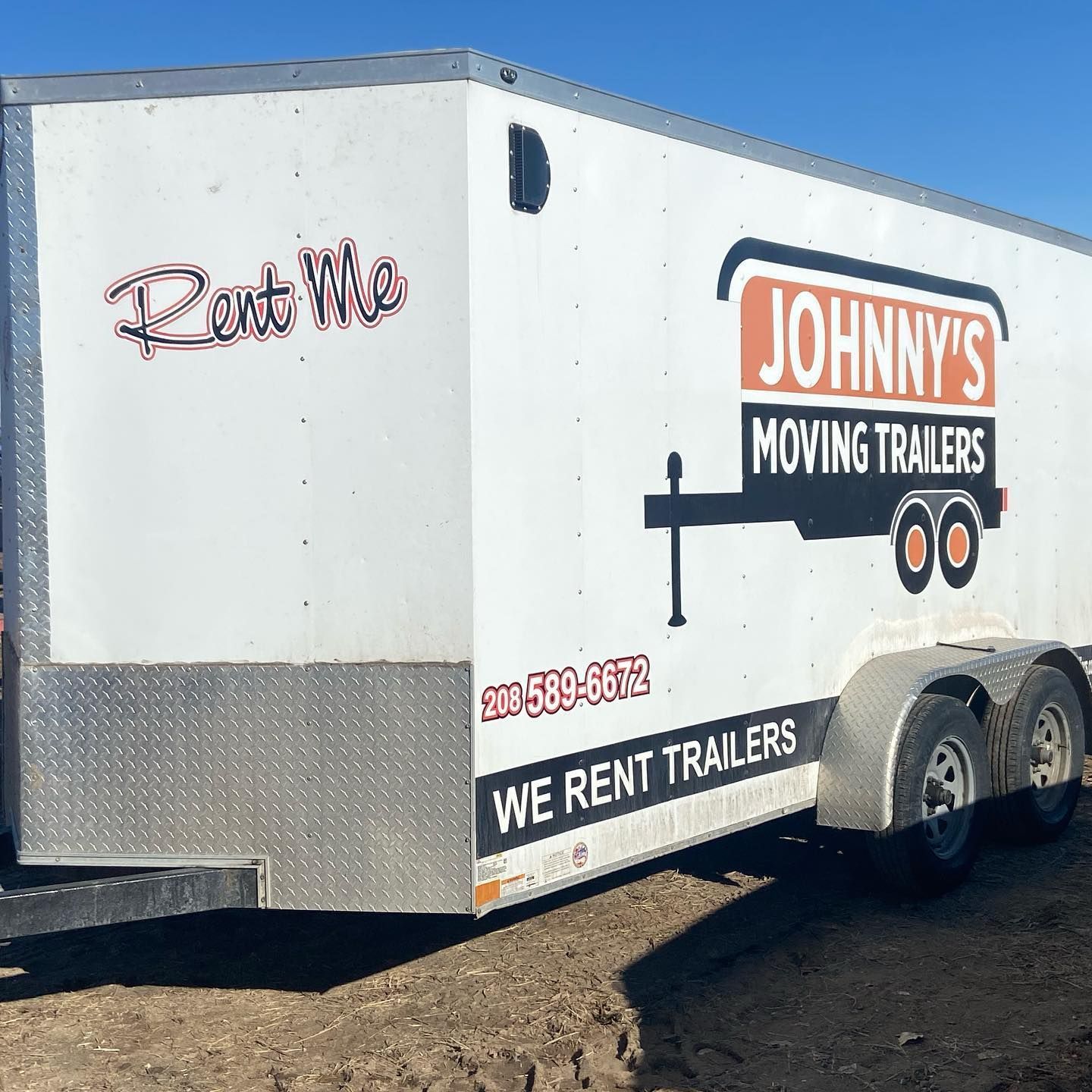 A johnny 's moving trailer is parked in the dirt