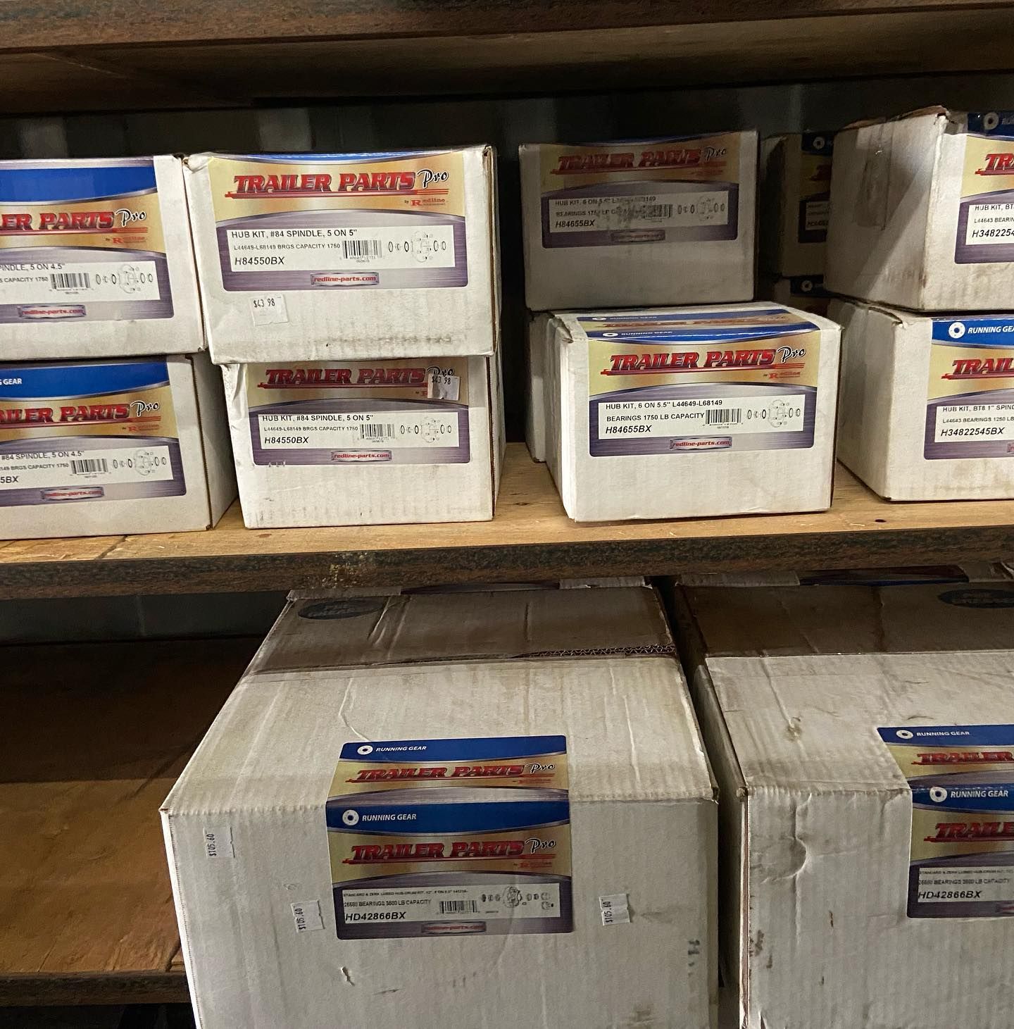 Boxes of trailer parts are stacked on a wooden shelf