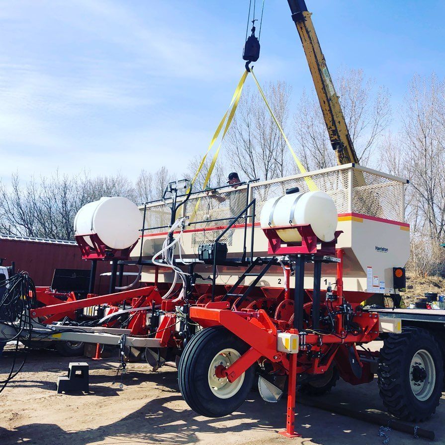 A crane is lifting a red and white tractor