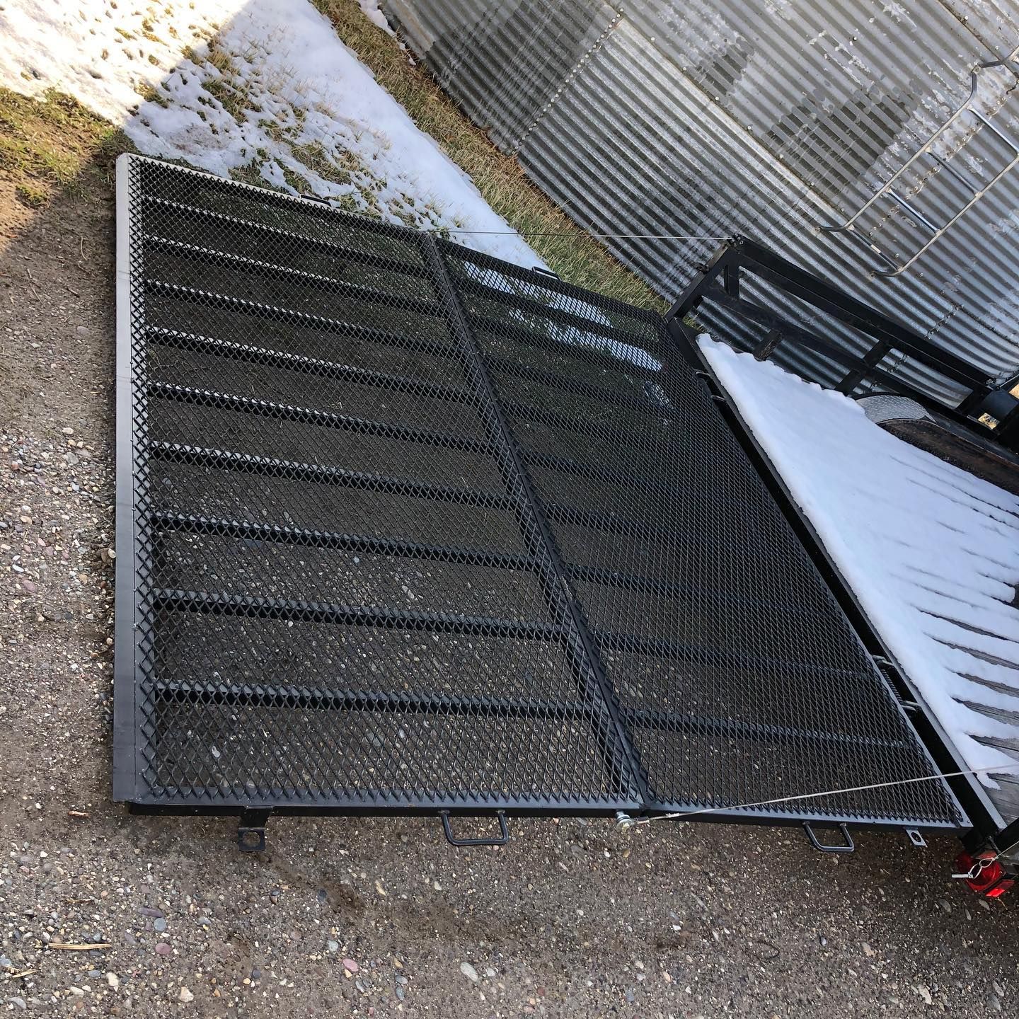 A metal ramp is sitting on the ground next to a fence.