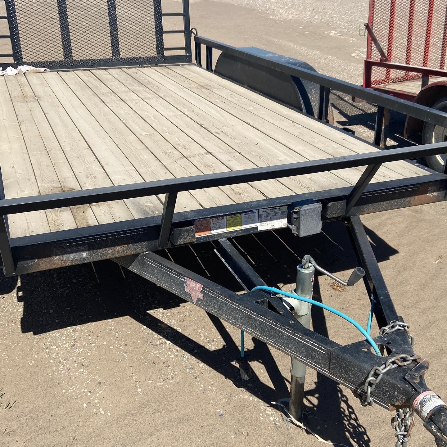 A trailer with a wooden deck is parked on the ground