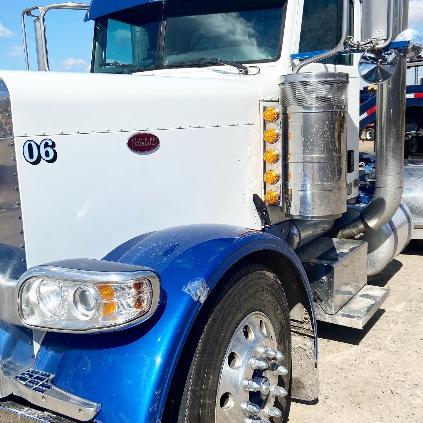 A blue and white semi truck with the number 06 on the front