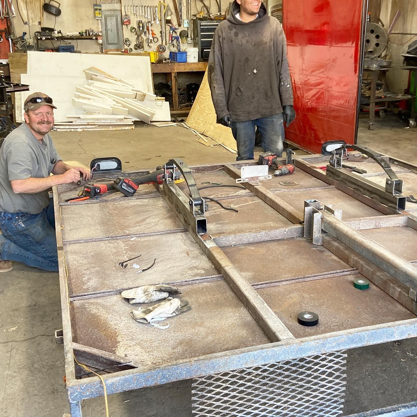 Two men are working on a metal structure in a workshop.