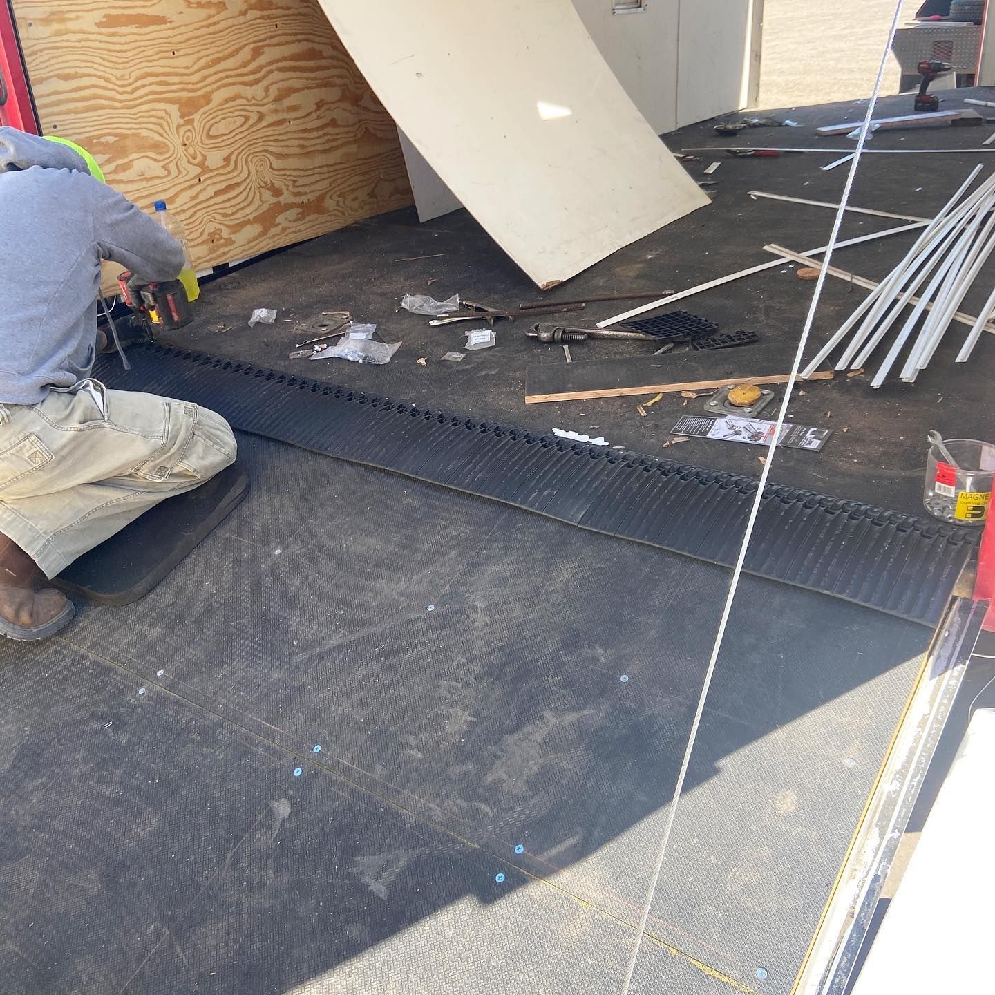 A man is kneeling on the ground in front of a trailer.