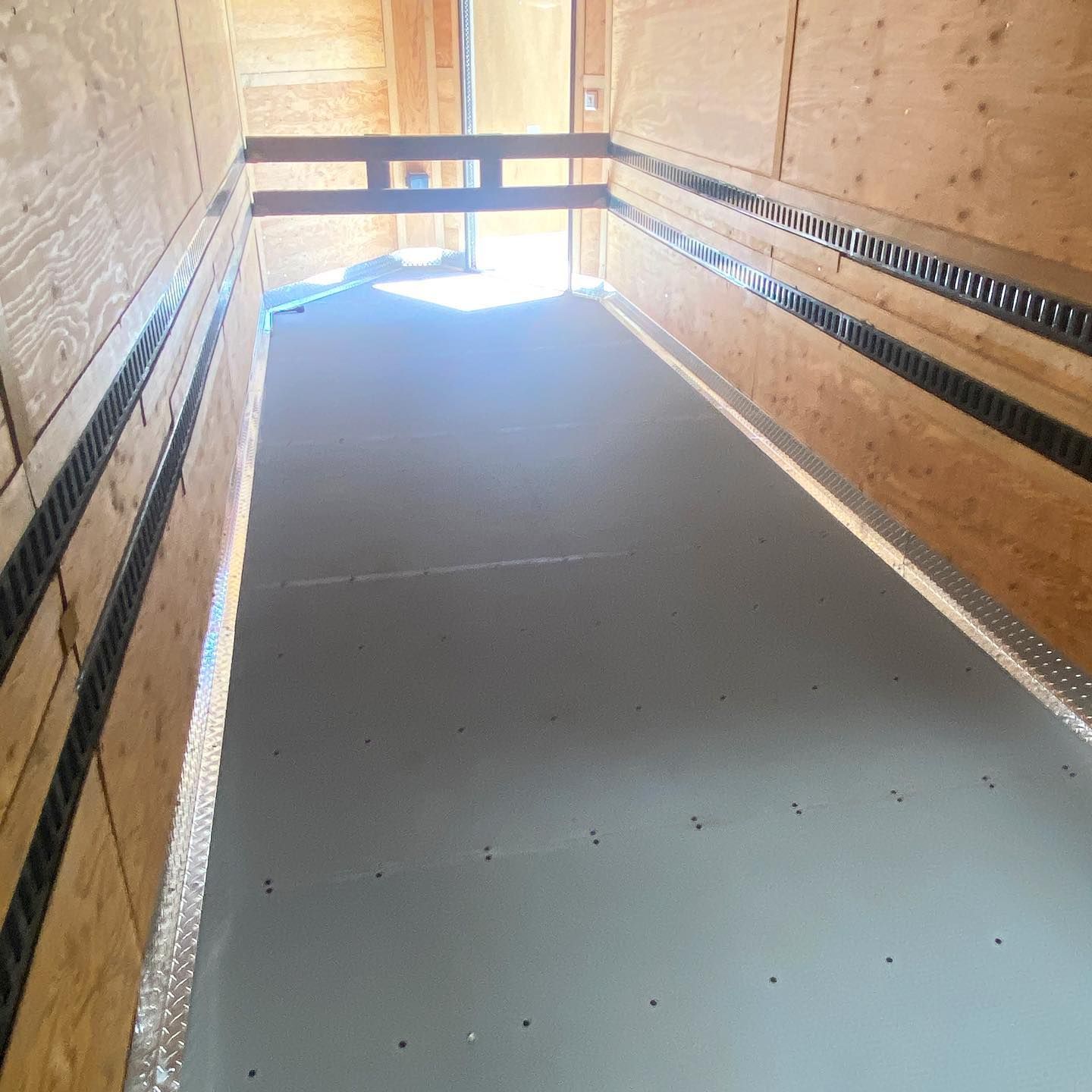 The inside of a wooden trailer with a gray floor.
