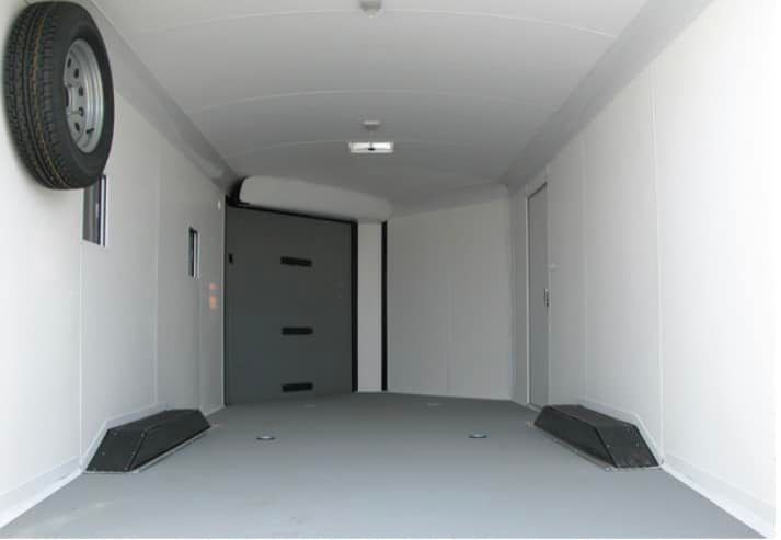 The inside of a trailer with a tire on the wall.