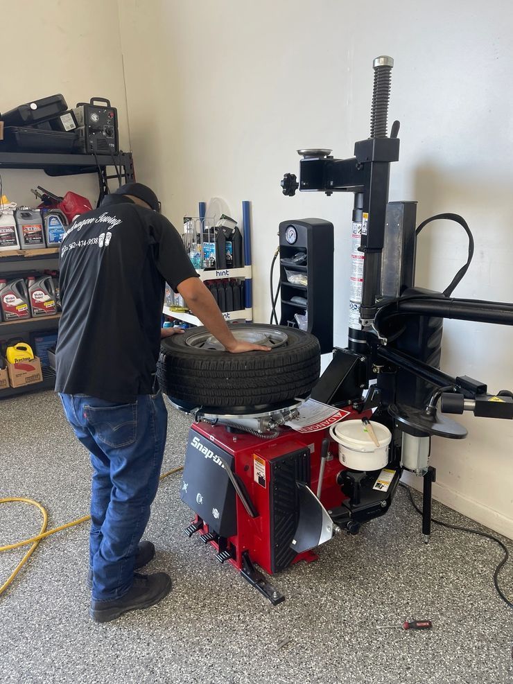 Mechanic changing a tire on a red tire-changing machine in a garage