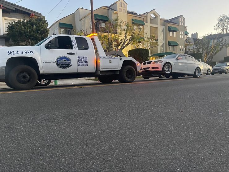Tow truck loading a white sedan on a residential street at dusk