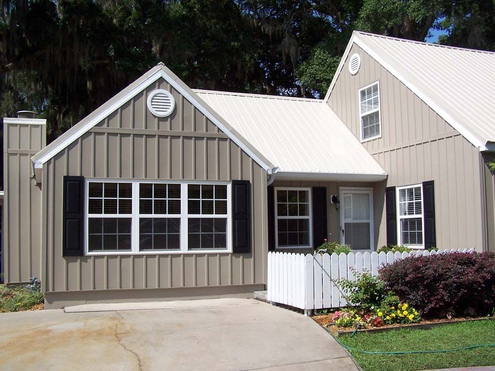 Tan house with white trim, black shutters, and a white picket fence.