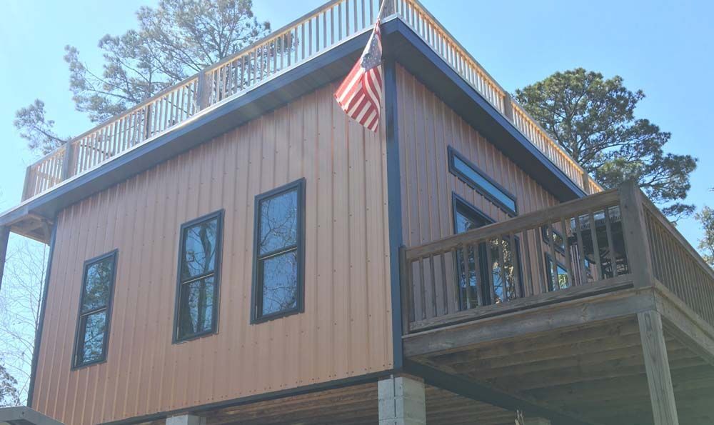 Brown cabin with a deck, a rooftop deck, and an American flag.