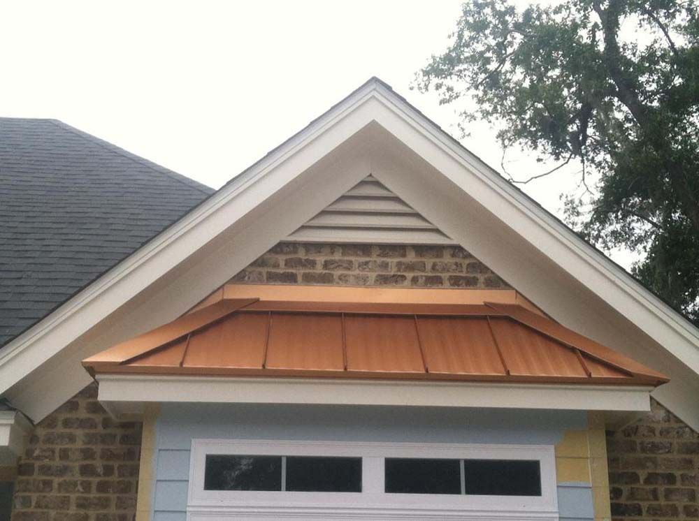 Garage facade with a copper-colored roof and light brick, under a gabled roof with white trim.
