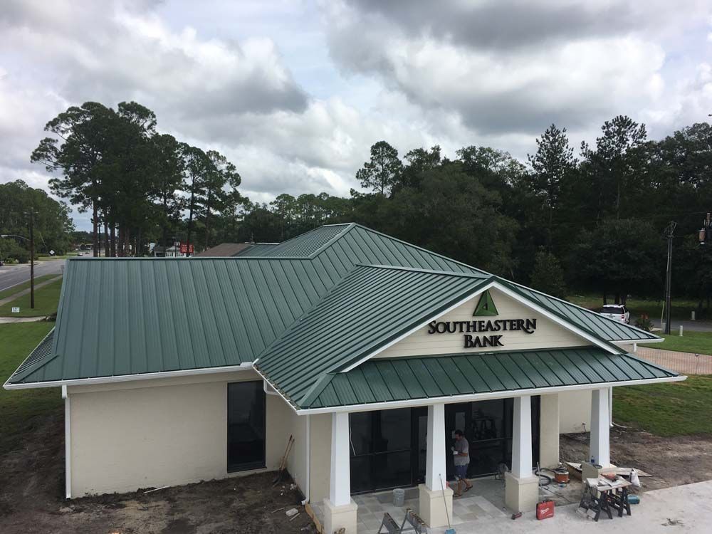 Southeastern Bank building with green metal roof, white trim, and cloudy sky.