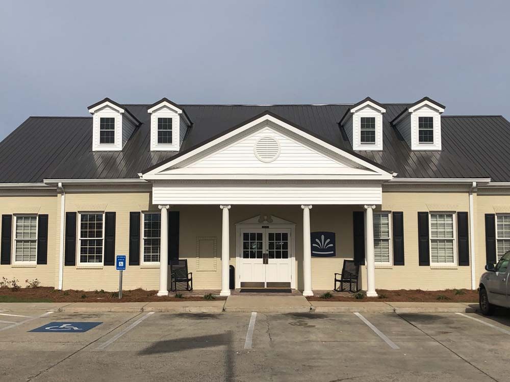 Tan building with black roof and white trim; accessible parking space.