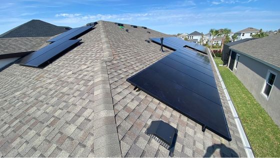 There are many solar panels on the roof of a house.