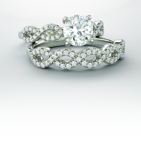 Two diamond rings, one with a large center stone, the other with a linked infinity band, on a white surface.