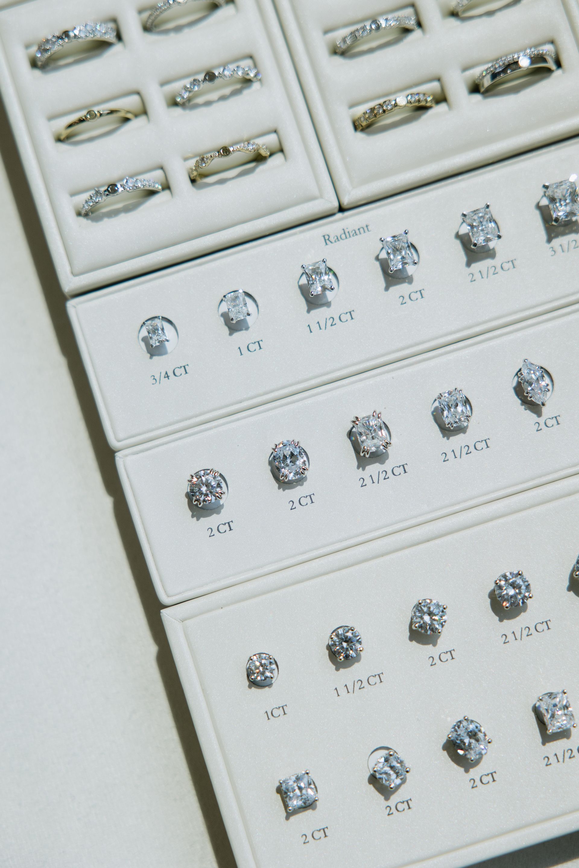 Jewelry display case with rings and diamond stud earrings in various sizes.