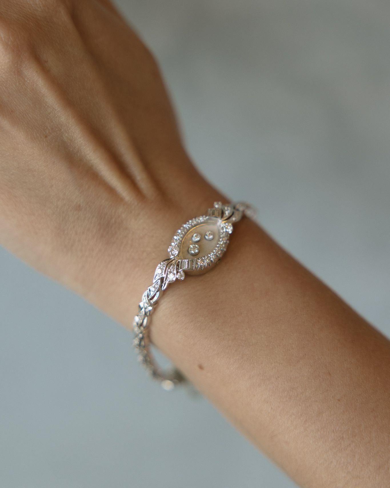 Bracelet with oval, gem-studded centerpiece, worn on a fair-skinned wrist.