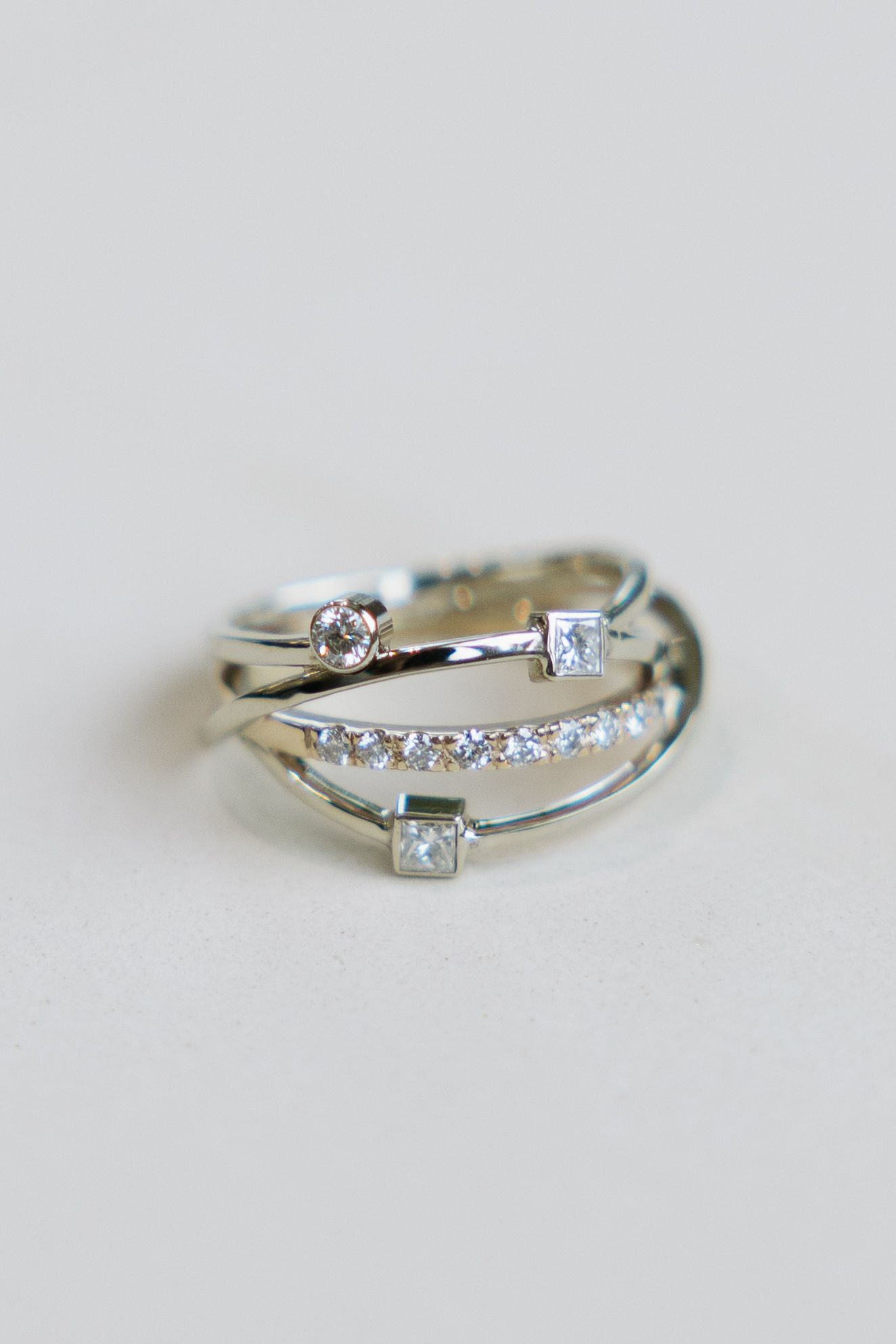 Silver ring with multiple bands and small diamonds on a white surface.