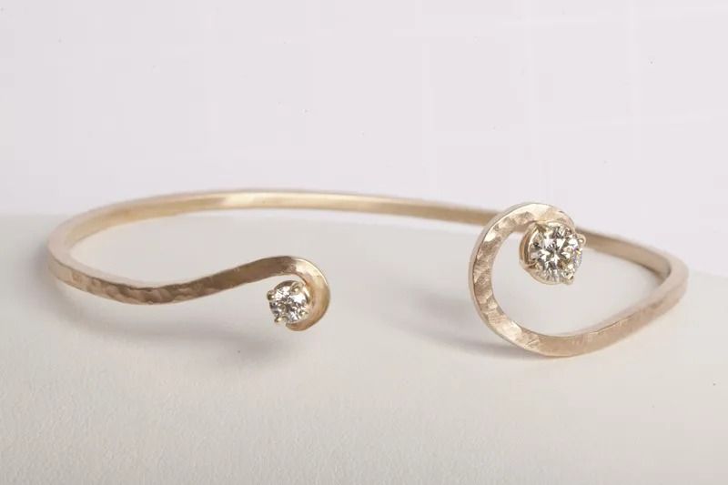 Gold-colored open cuff bracelet with hammered texture, featuring a spiral end and a diamond.
