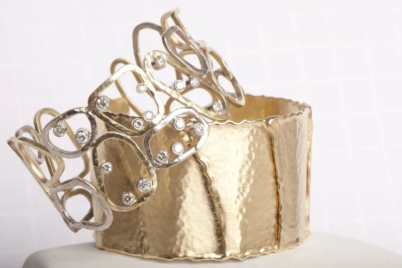 Gold and diamond bracelet, cuff style, with openwork design, resting on a textured gold base.