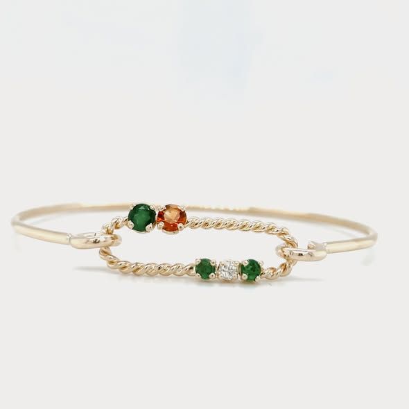 Gold bracelet with green, orange, and white gemstones in a twisted oval design.