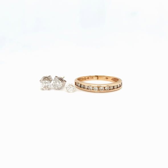 Jewelry set: diamond stud earrings and a gold band ring on a white background.