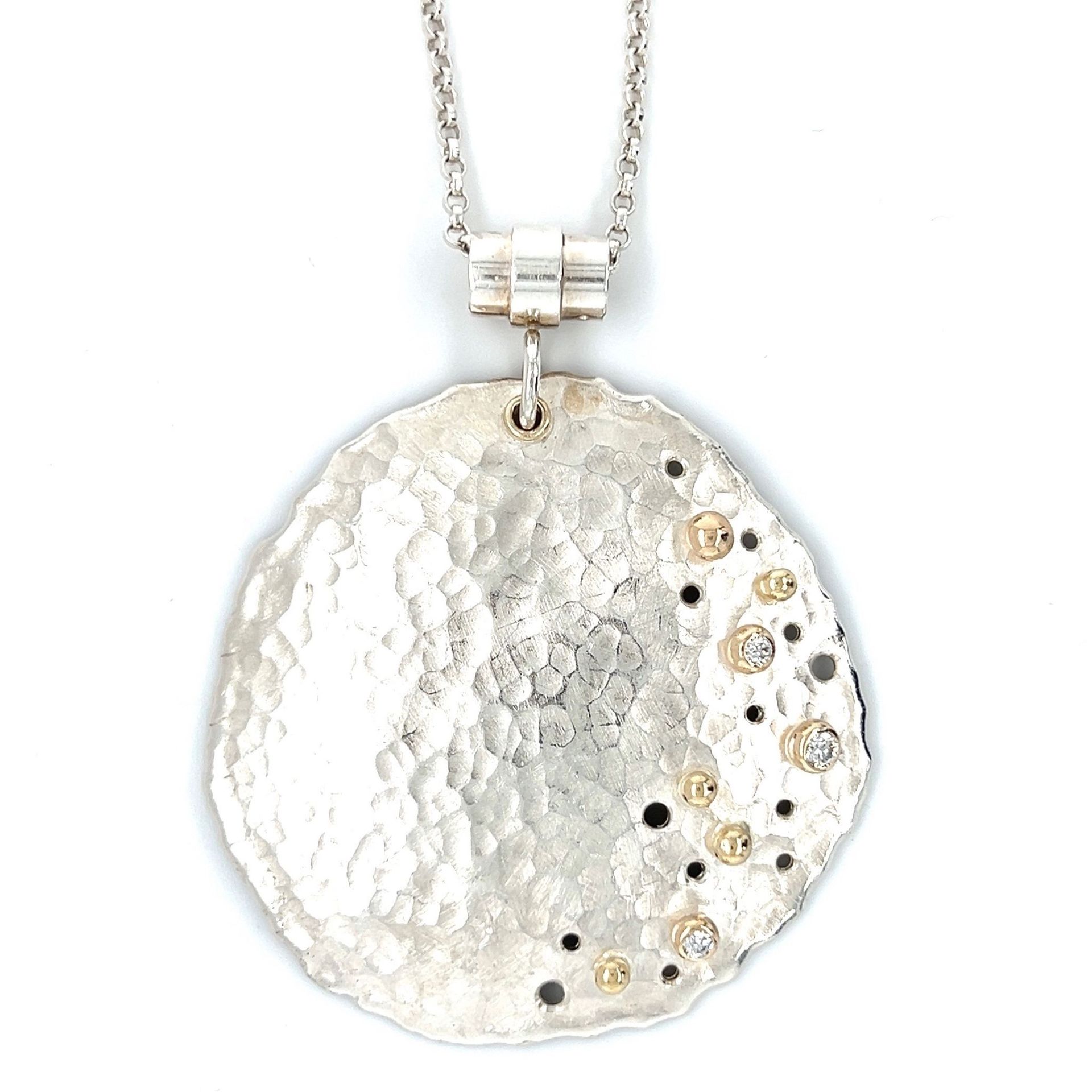 Silver pendant necklace with hammered texture, gold accents, and a stone-set, irregular circle pendant.