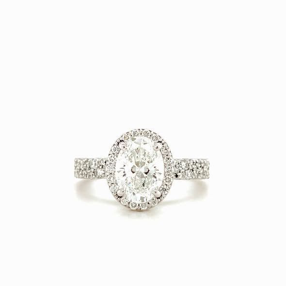 Oval diamond ring with halo setting and diamond-encrusted band.