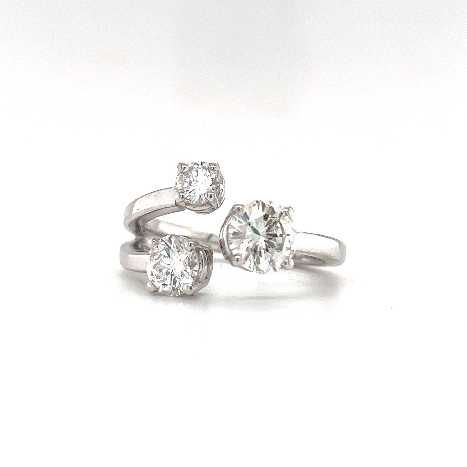 Silver ring with three clear gemstones, two square and one round, set on a white surface.