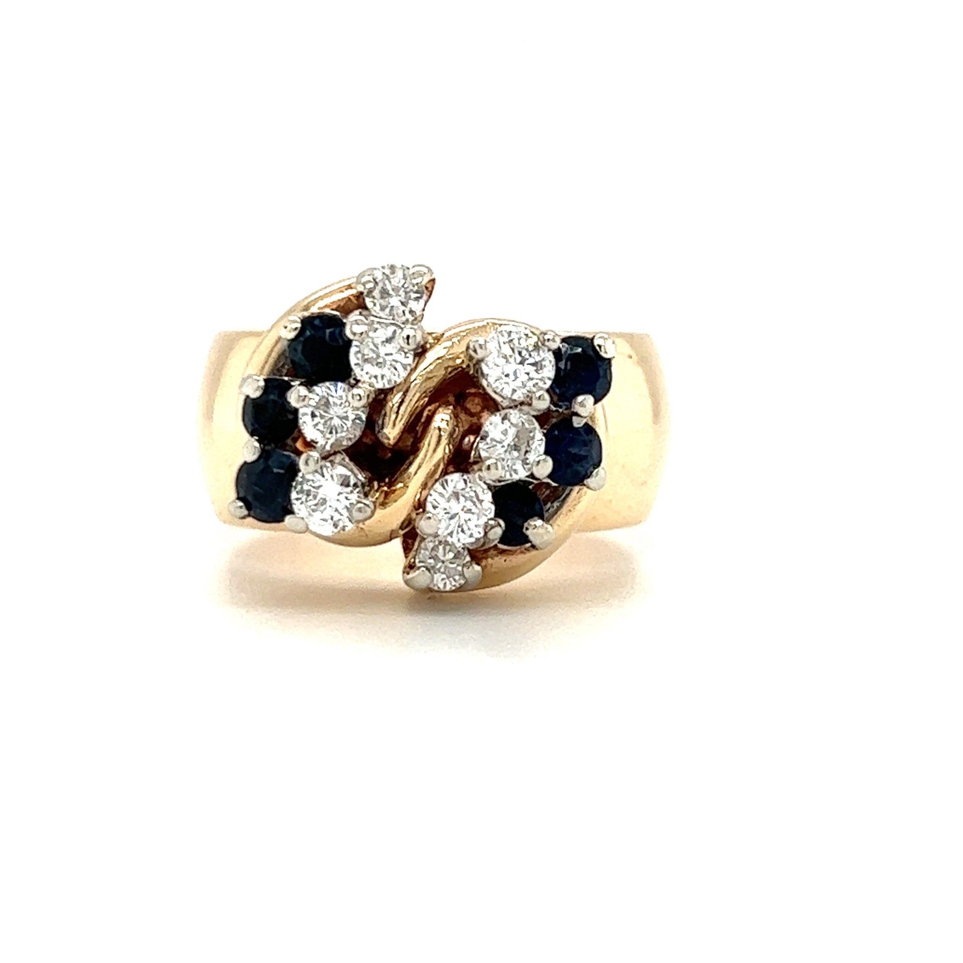 Gold ring with white diamonds and dark blue sapphires in a swirling design.